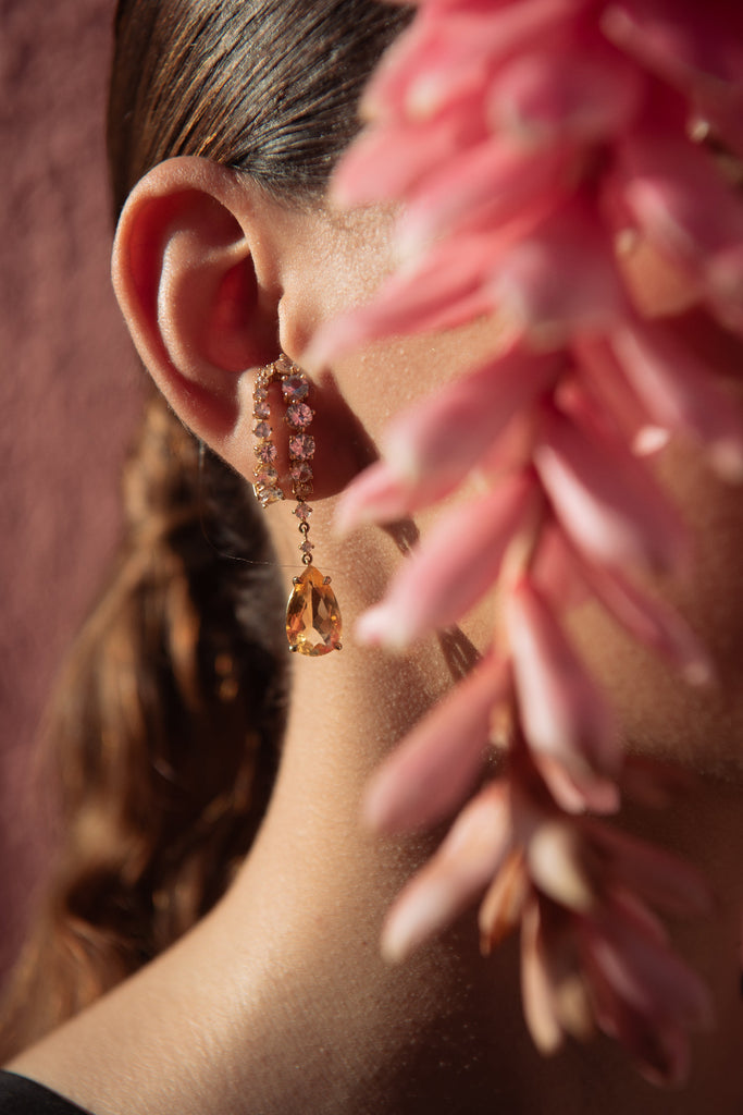 Close-up of an earring with a pink flower in the foreground