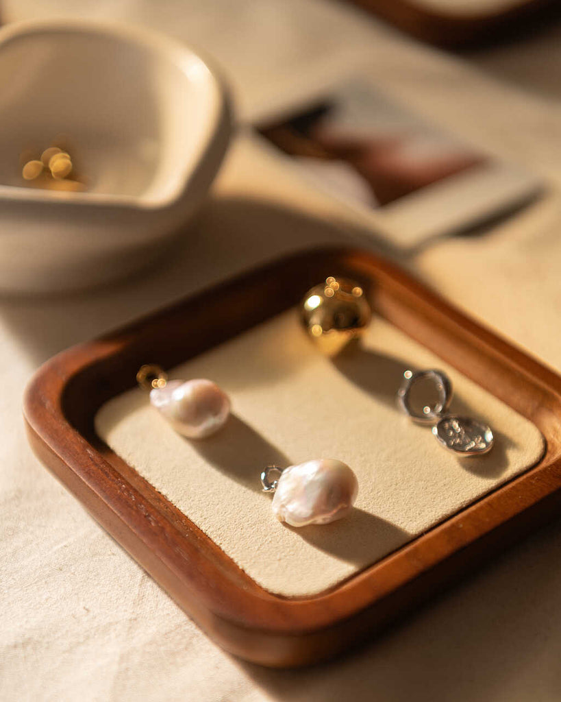 wodden jewelry display featuring pearls and coin charms