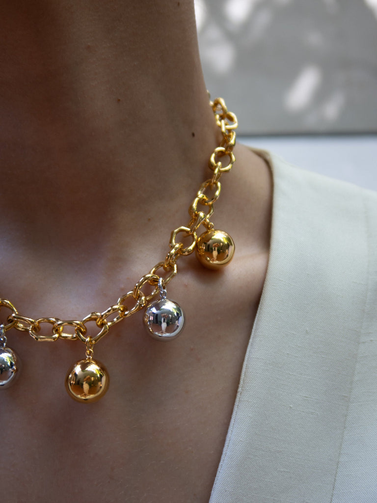 close up of gold chain link necklace with ball charms 