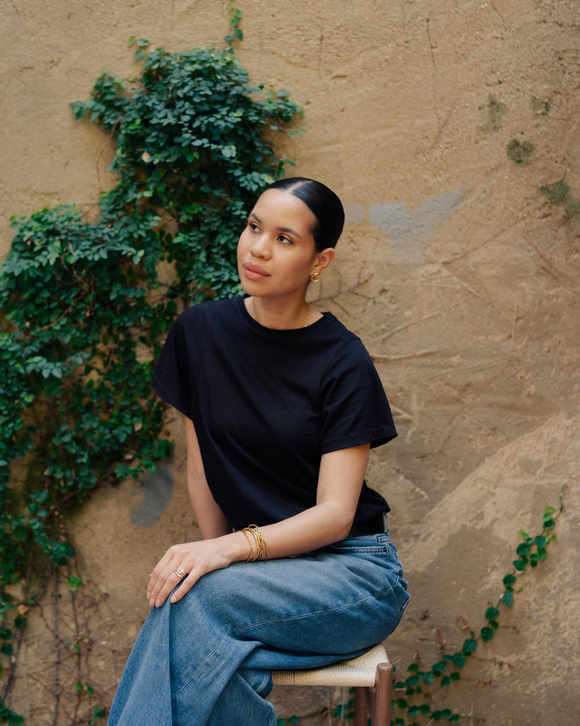 Person sitting on a chair against a textured wall with greenery