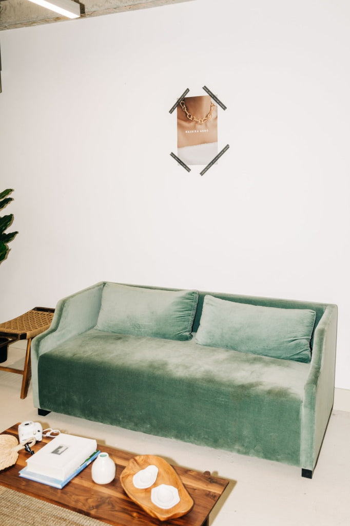Green velvet sofa in a modern living room with a wooden coffee table and decor items.