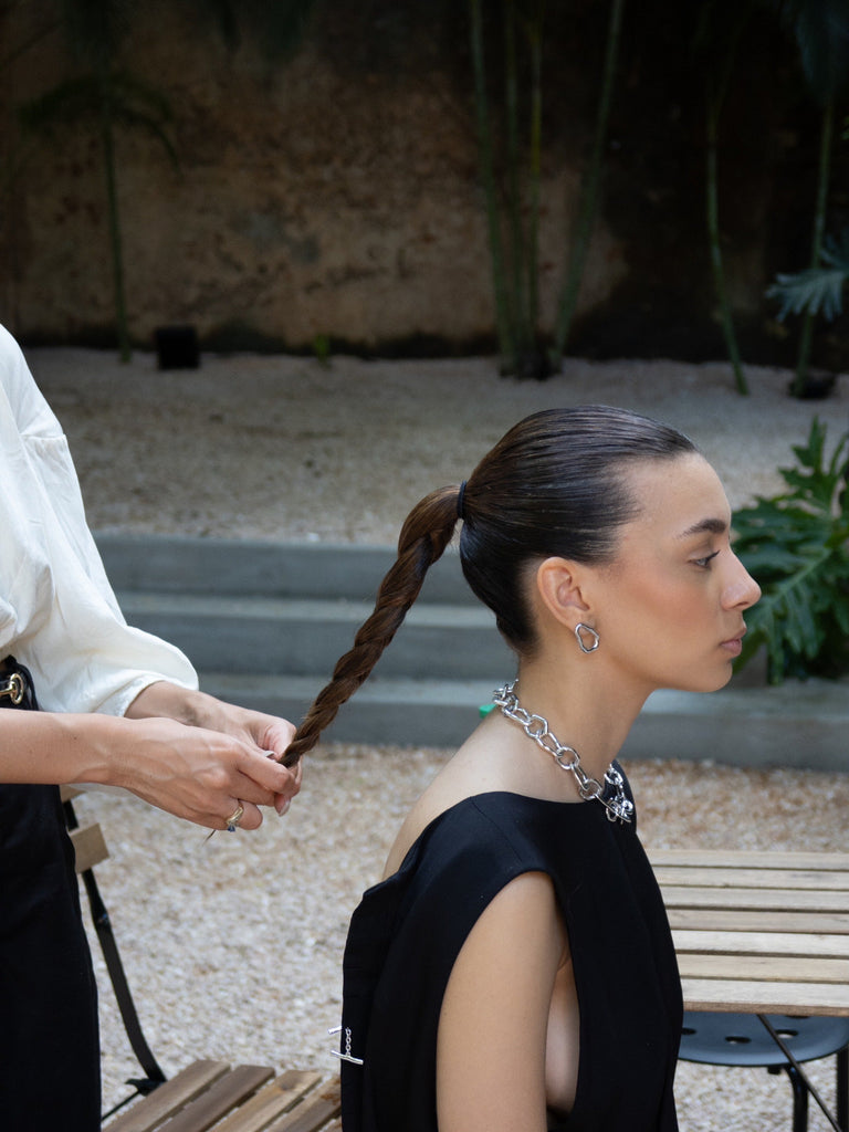 Person getting their hair styled outdoors with a blurred background
