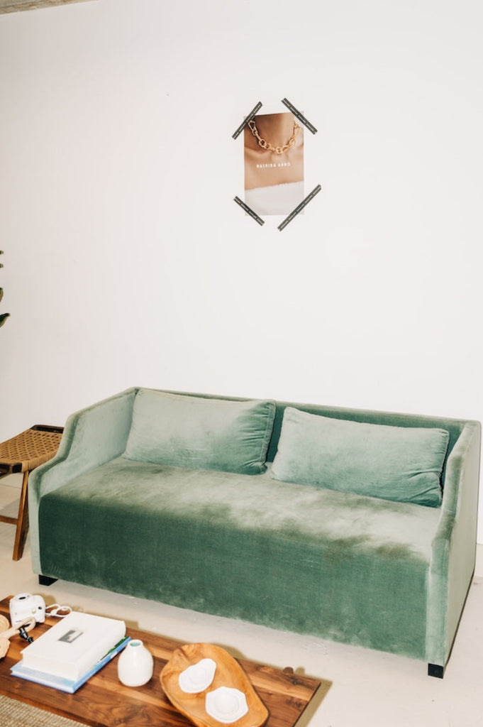 Green velvet sofa in a modern living room with a wooden coffee table and decor items.