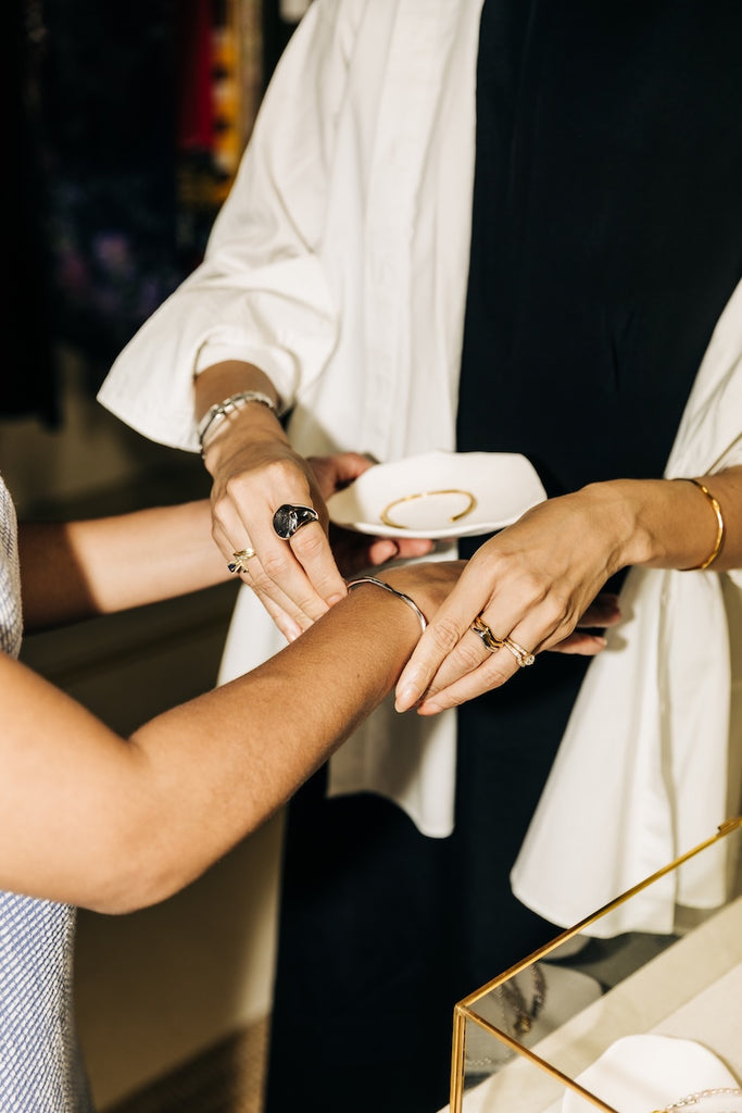 Person wearing a ring, with another person adjusting it on their finger.