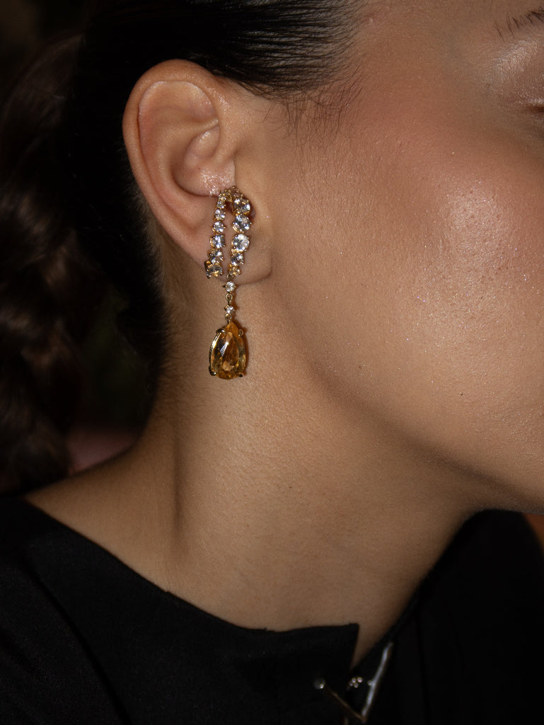 Close-up of a person wearing a teardrop-shaped earring with a dark background
