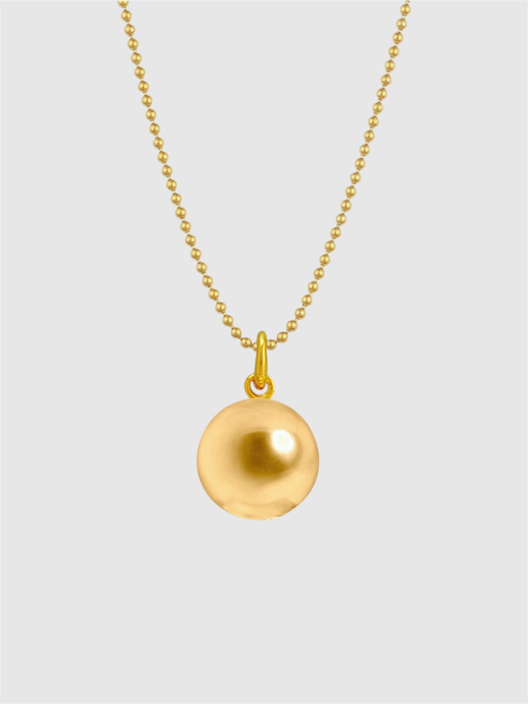 Gold necklace with a round pendant on a light gray background