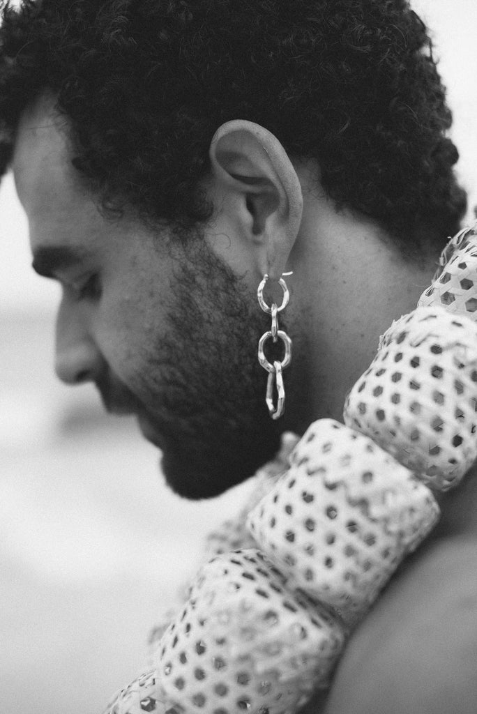 Black and white close-up of a man wearing a chain earring.