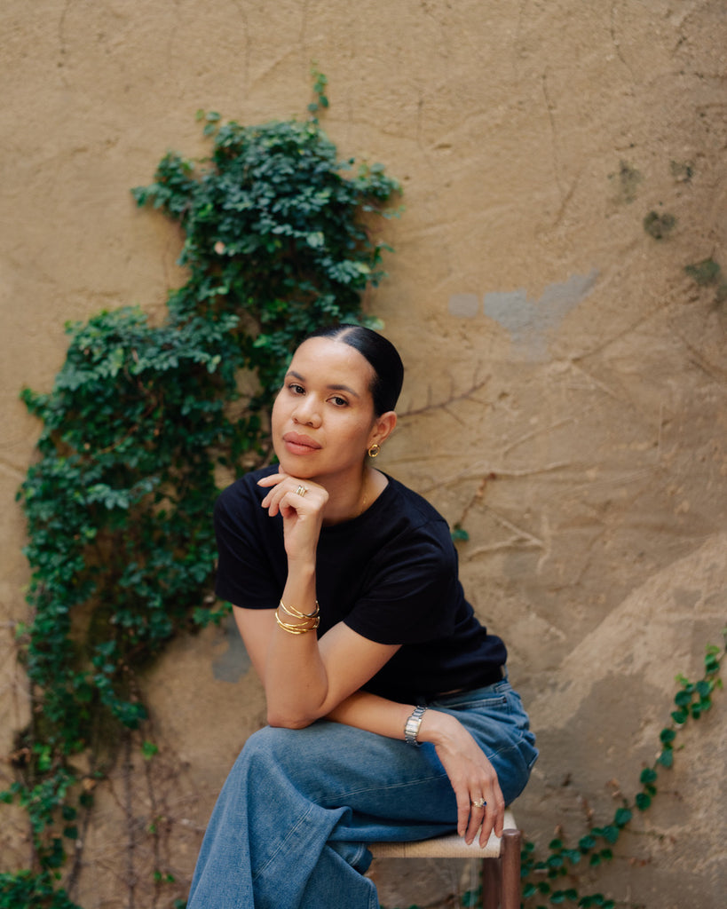 Woman sitting against a textured wall with greenery