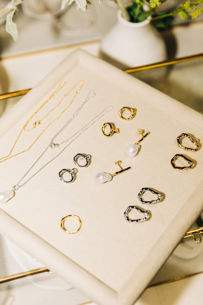 Collection of gold earrings on a beige jewelry box with a blurred background