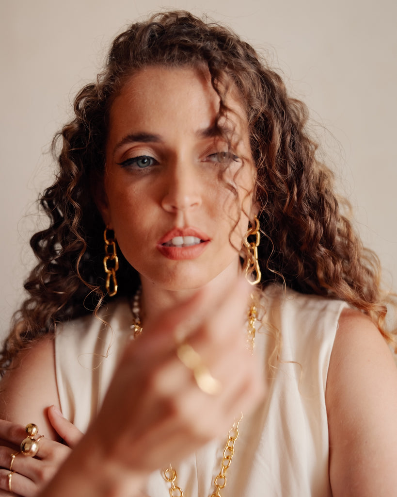 Woman wearing gold jewelry against a neutral background